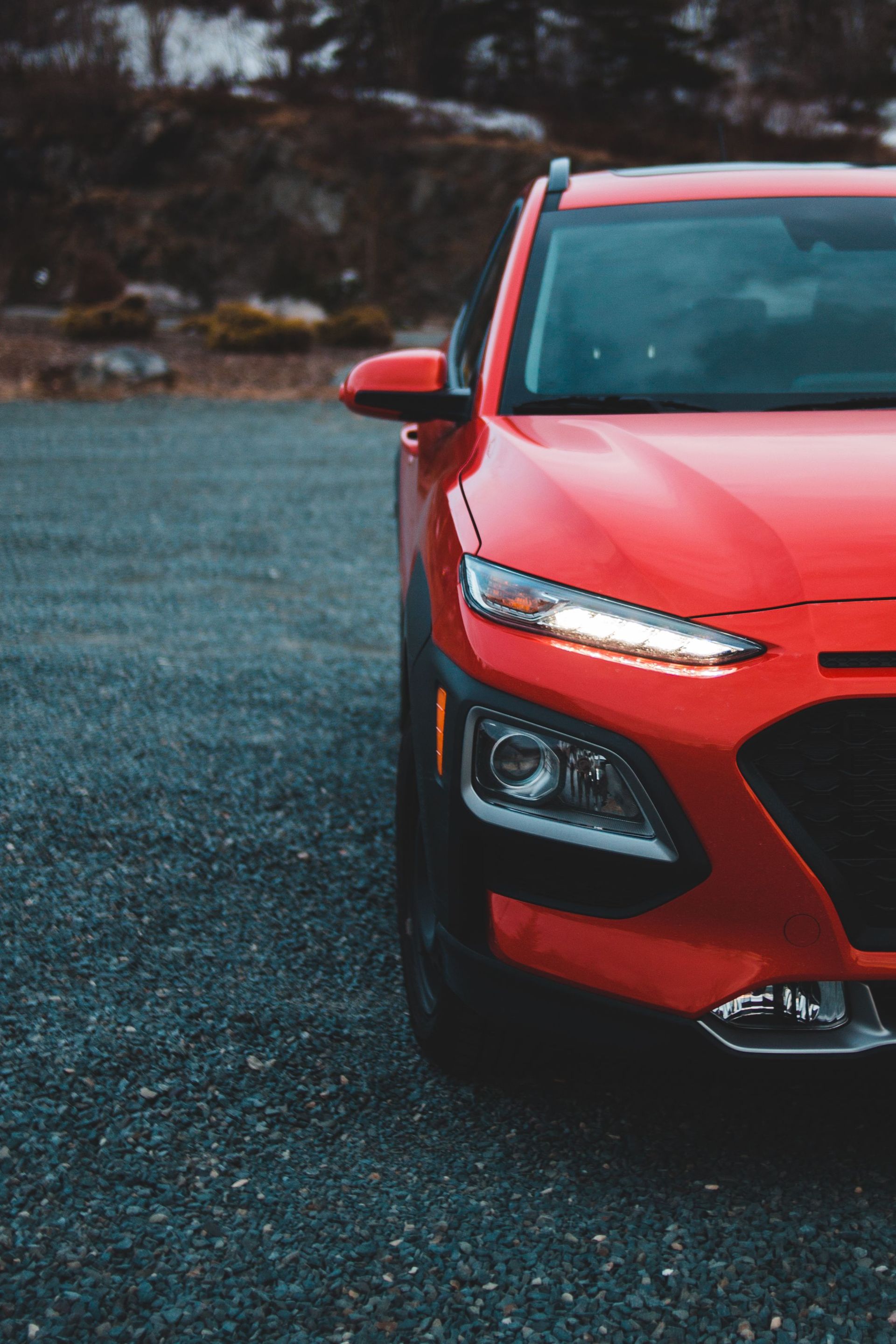Half of front of modern car of red color parked on asphalt road