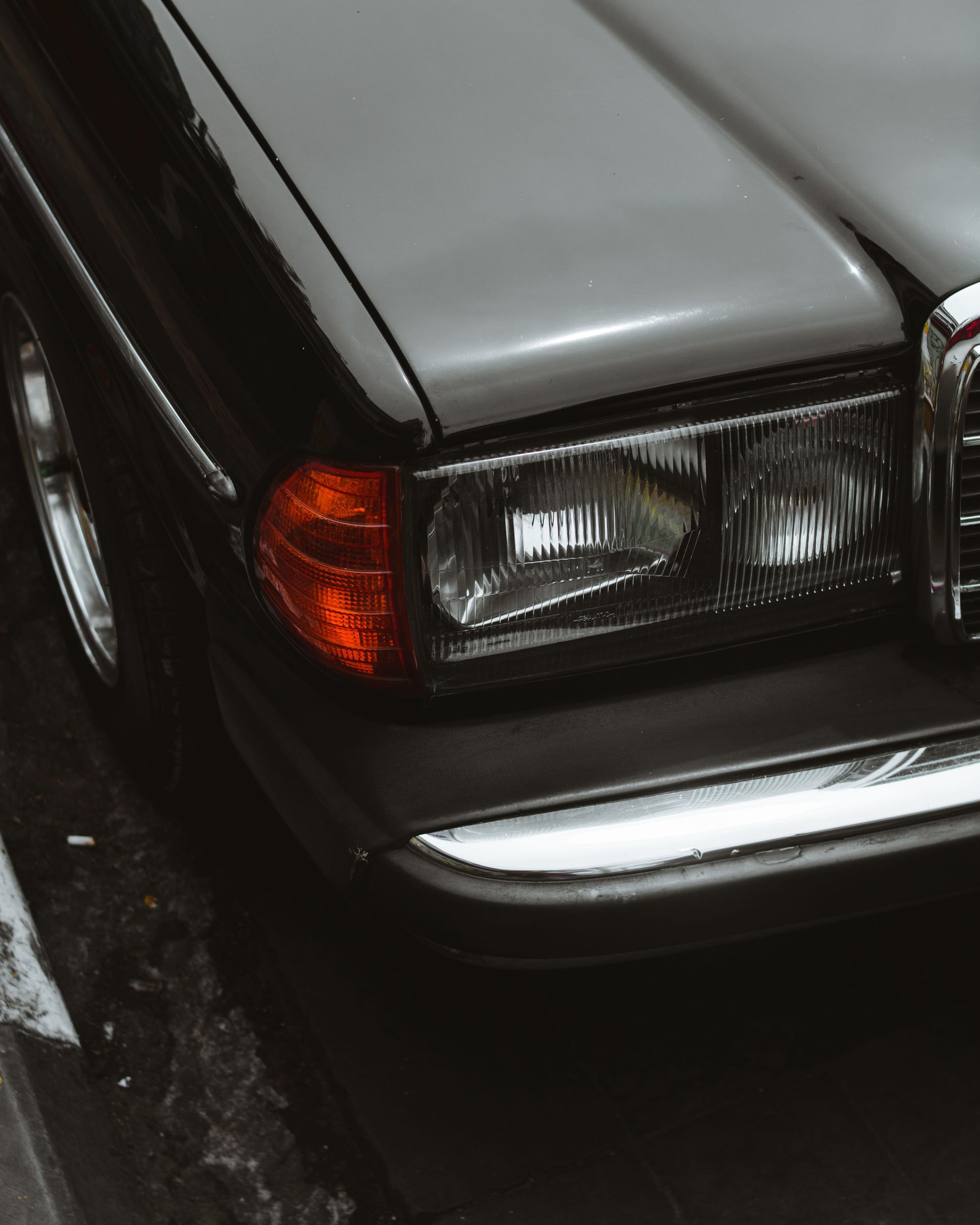 Close-up view of a vintage car's front headlight and bumper, ideal for automotive enthusiasts.