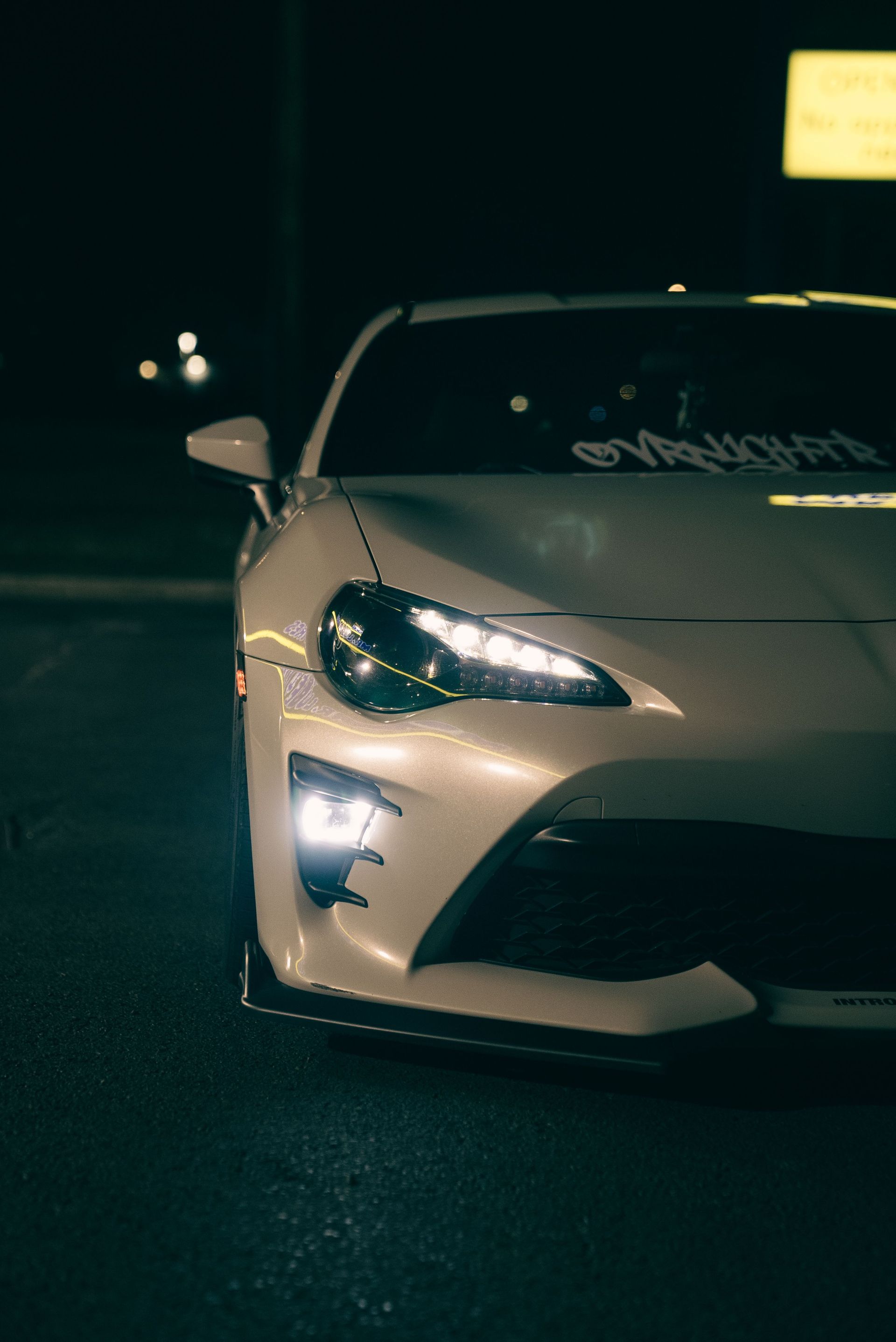 Front view of a modern sports car with headlights on, captured at night. Moody lighting accentuates the sleek design.