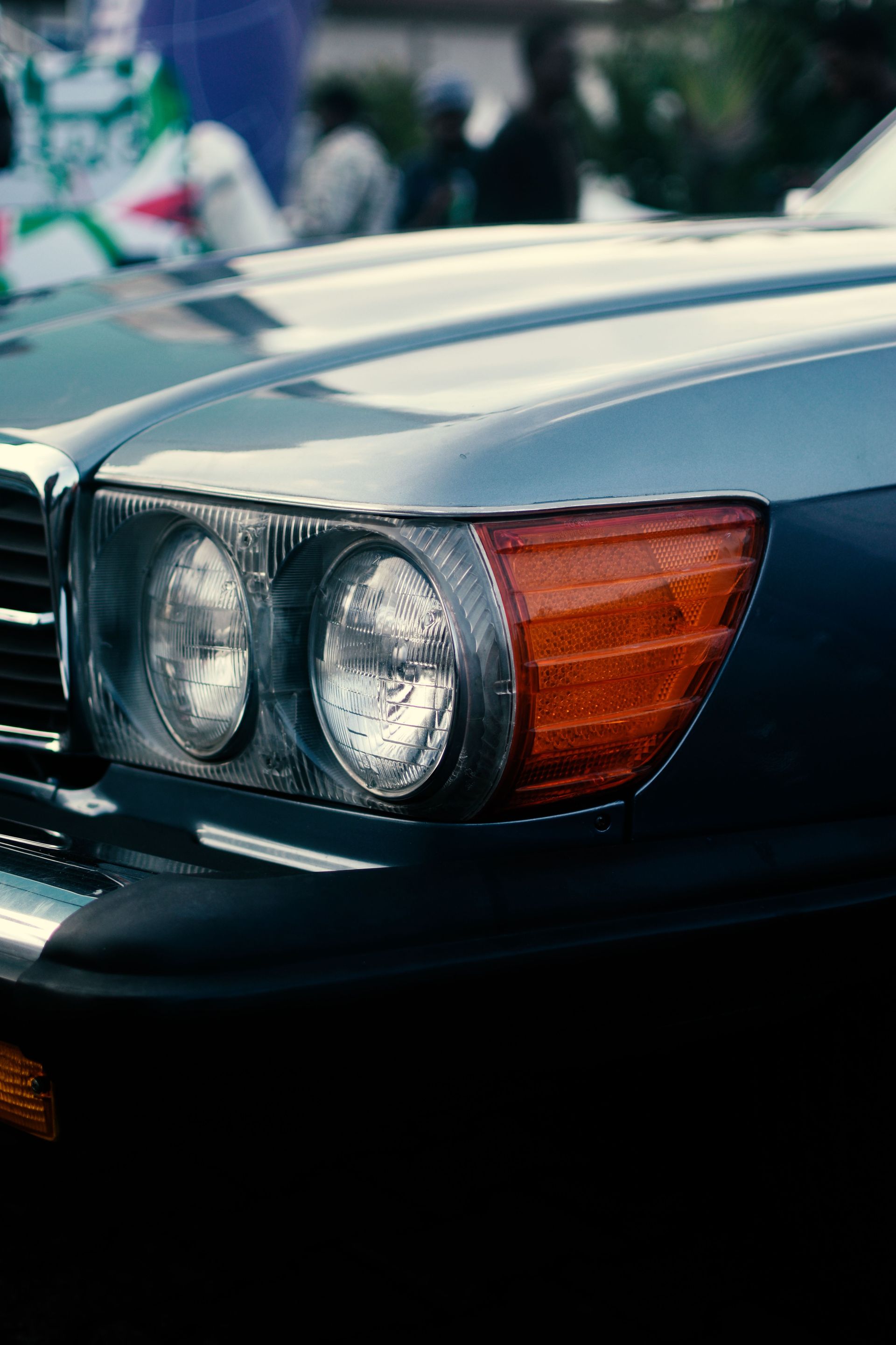 Captured close-up of a vintage car's front headlight, showcasing timeless automotive design.