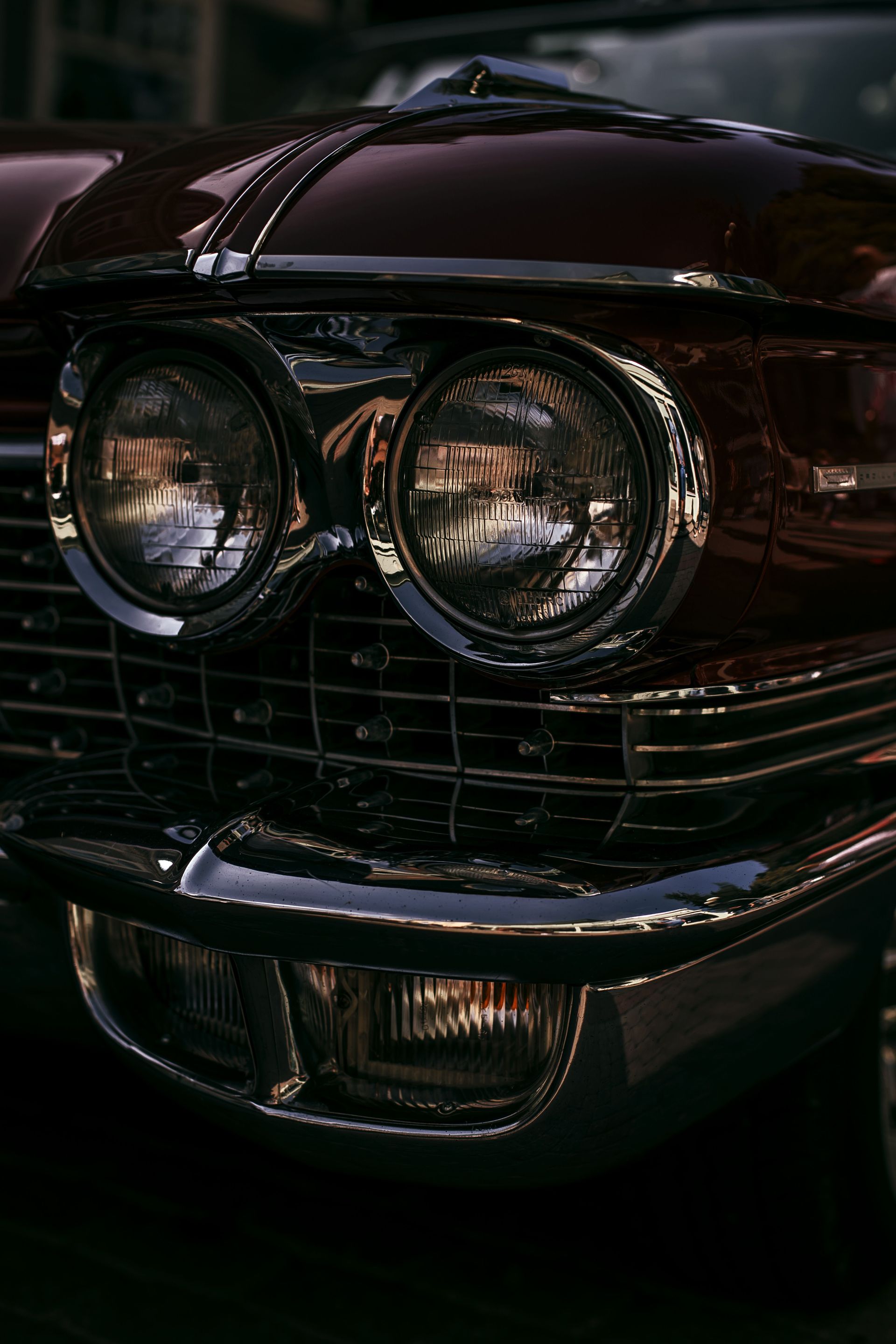 Dramatic low-light shot of vintage car headlights showcasing chrome details.